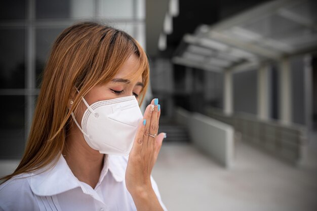 Foto asiatische frau trägt n95-maske zum schutz vor staub pm 25 ökologie-konzept allergie kopfschmerzen luftgefahr in der stadt