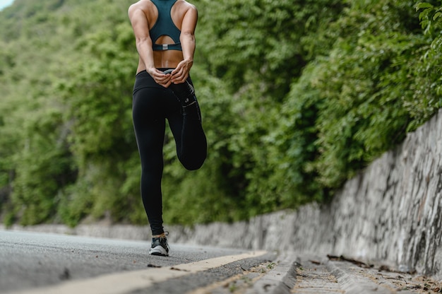 Asiatische Frau trainiert an den Wochenendübungen und streckt ihren Körper auf der Straße und ist üppig schön. Gesundes, sportliches Fitness- und Lifestyle-Konzept.