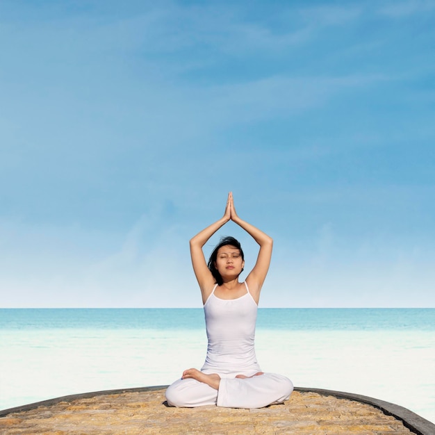 Asiatische Frau übt Yoga am Strand