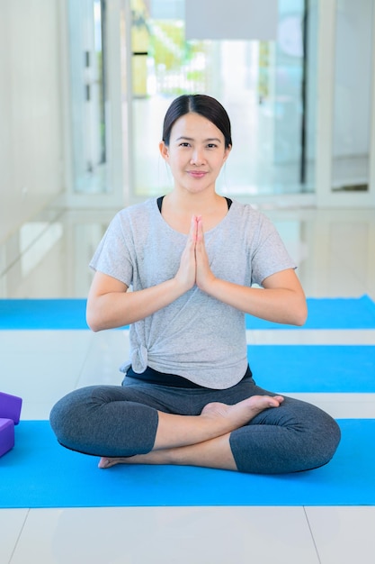 Asiatische Frau Yoga Atmung und Meditation allein im Fitness-Studio. Indoor-Übungen und Workouts für Gesundheit und Wohlbefinden.