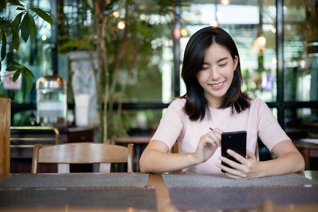 Asiatische Frauen arbeiten und hören Musik auf Mobiltelefonen.