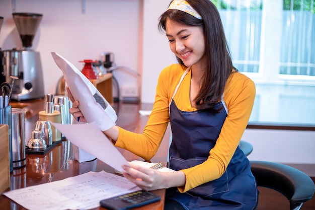 Asiatische Frauen Barista lächelnd und mit Kaffeemaschine in Café-Theke Arbeitende Frau Kleinunternehmer Essen und Trinken Café-Konzept