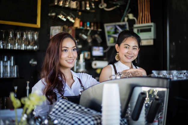 Asiatische Frauen Barista lächelnd und mit Kaffeemaschine in Coffeeshop-Theke - Working Woman Kleinunternehmer Inhaber Essen und Trinken Cafe Konzept