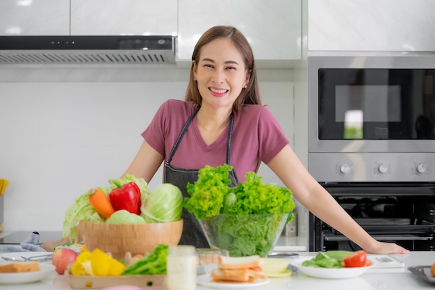 Asiatische Frauen, die in der Küche lächeln und Salatgemüse kochen, ernähren sich gesund