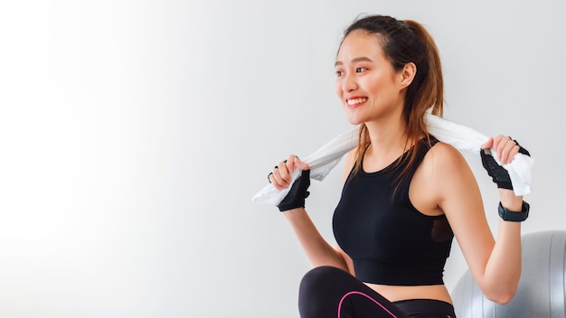 Asiatische Frauen, die nach dem Spielen Yoga ruhen und zu Hause Hintergrund mit Kopienraum trainieren.