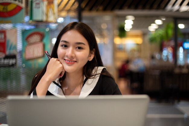 Asiatische Frauen, die online mit Computernotizbuch arbeiten und lernen. sie lächelt und ist glücklich