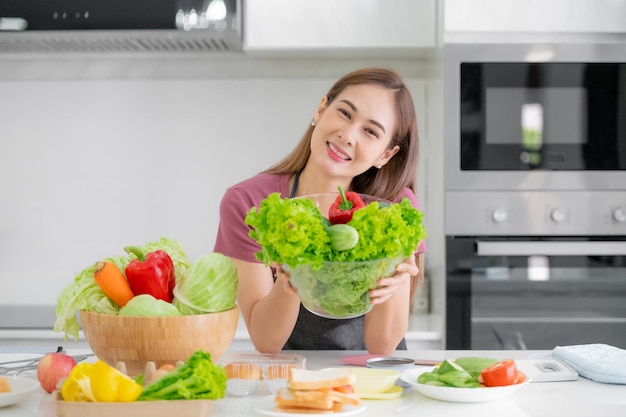 Asiatische Frauen, die Salatgemüse aus biologischem Anbau kochen, ernähren sich gesund in der Küche zu Hause