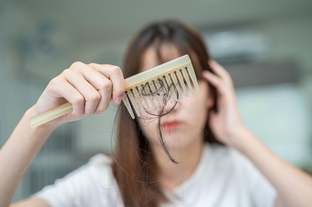 Asiatische Frauen haben Probleme mit langem Haarausfall, der an der Kammbürste befestigt ist