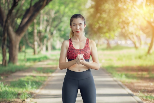 Asiatische Frauen hören Musik während eines Trainings im Park.