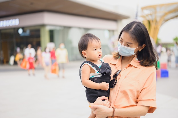 Asiatische Frauen in steriler Schutzmaske mit ihrem Sohn. Luftverschmutzung, Virus, Coronavirus-Konzept