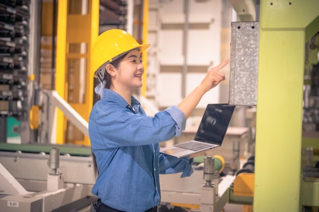 Asiatische Frauen sind Ingenieurinnen, die Maschinen in der Fabrik mit Computer inspizieren Asiatische Ingenieurin, die im Fabrikkonzept arbeitet