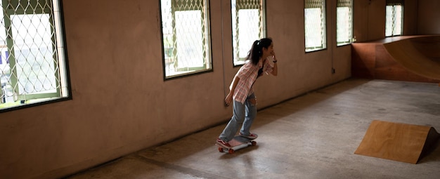 Asiatische Frauen surfen Skate oder Skates Board Indoor schöner Sommertag Sportaktivität Lifestyle-Konzept