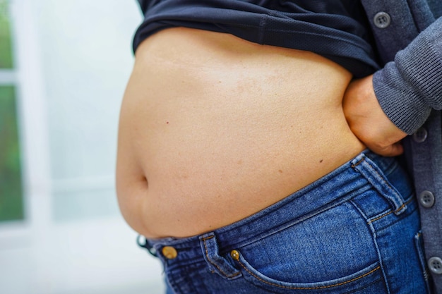 Asiatische Frauen zeigen dicken Bauch, große Größe, Übergewicht und Fettleibigkeit im Büro