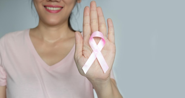 Asiatische Frauen zeigen rosafarbenes Schleifenband in ihrer Hand, um Brustkrebspatientinnen zu ermutigen Brustkrebskampagne im Oktober