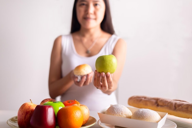 Asiatische Frauenhände, die grünen Apfel und Brot auf weißem Hintergrund halten, gesunde Ernährung, Diätkonzept