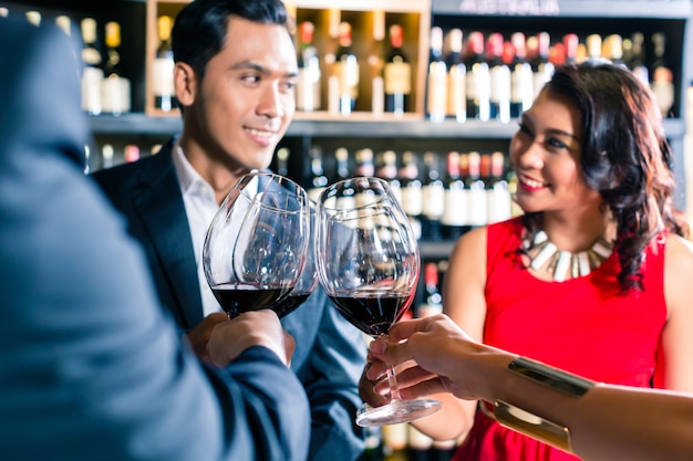 Asiatische Freunde, die mit Rotwein in der Bar rösten