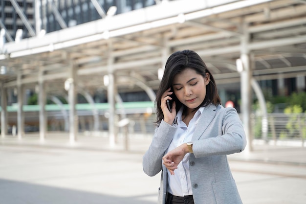 Asiatische Führungskraft, die mit einem Mobiltelefon auf der Straße arbeitet