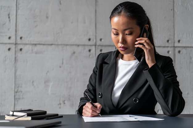 Asiatische Geschäftsfrau am Telefon Notizen machen