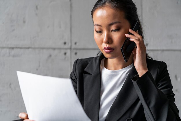 Asiatische Geschäftsfrau am Telefonlesebericht