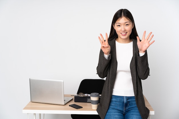 Asiatische Geschäftsfrau an ihrem Arbeitsplatz isoliert beim Zählen von acht mit den Fingern