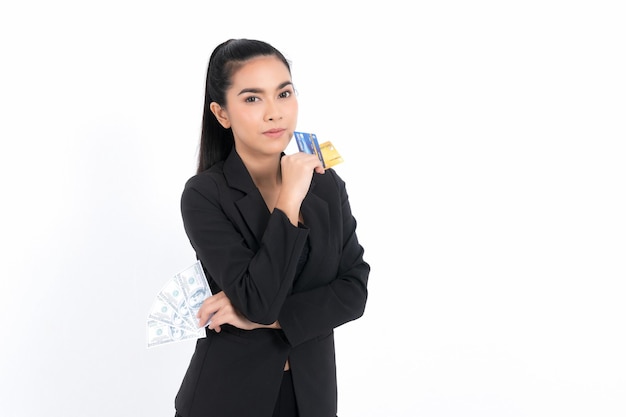 Asiatische Geschäftsfrau des Porträts mit dem Zeigen des Bündels Geldbanknoten und dem Halten der Kreditkarte in der Hand lokalisiert auf weißem Hintergrund. Konzeptgeschäft und Kredit.