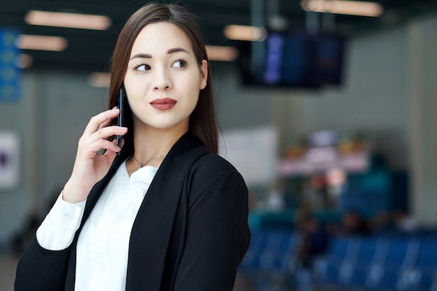 Asiatische Geschäftsfrau, die am Telefon spricht. Porträt des schönen Mädchens im Büro oder im Besprechungsraum