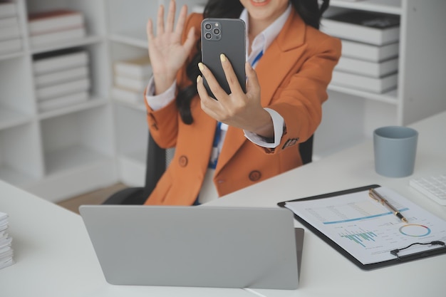 Asiatische Geschäftsfrau, die einen Laptop-Computer verwendet und im Büro mit einem Taschenrechnerdokument auf dem Schreibtisch arbeitet, um die Analyse des Finanzberichts-Geschäftsplan-Investitionsfinanzierungsanalysekonzepts zu planen