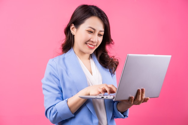 Asiatische Geschäftsfrau, die Laptop auf Rosa hält