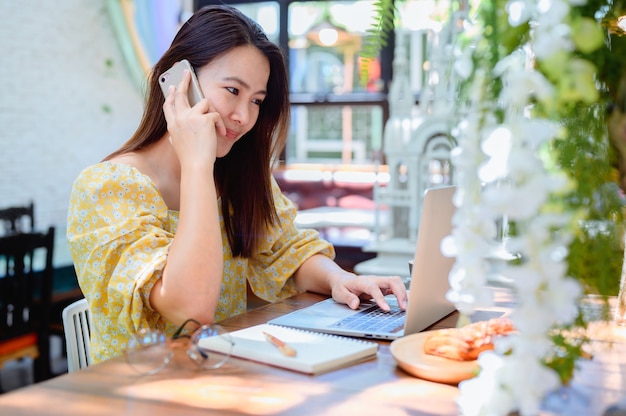 Asiatische Geschäftsfrau, die online im Café arbeitet. Thailändischer Frauenlebensstil mit Kaffee am Wochenende. Soziale Distanzierung und neue Normalität.