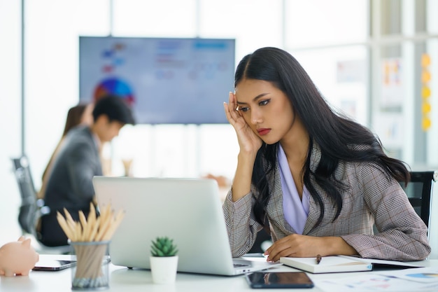 Asiatische Geschäftsfrau, die sich nach langer Arbeit gestresst und Kopfschmerzen fühlt Office-Syndrom-Konzept