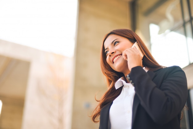 Asiatische Geschäftsfrau, die Smartphone smie Gesicht verwendet