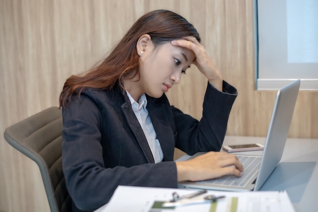 Asiatische Geschäftsfrau ernst über die harte Arbeit der Arbeit bis die Kopfschmerzen