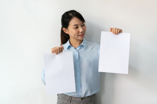 Asiatische Geschäftsfrau im blauen Hemd hält ein leeres Blatt Papier in den Händen für Werbung