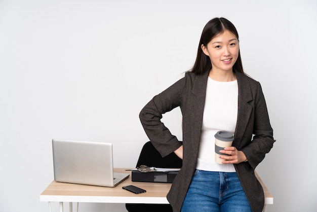 Asiatische Geschäftsfrau in ihrem Arbeitsplatz auf weißer Wand in der hinteren Position