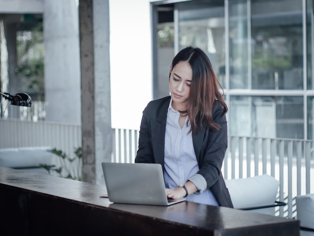 Asiatische Geschäftsfrau mit dem Laptop glücklich und Lächelnkonzept-Erfolgsarbeit