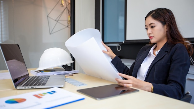 Asiatische Geschäftsfrau und Ingenieurin arbeitet in seinem Büro und prüft Zeichnungen und Dokumente