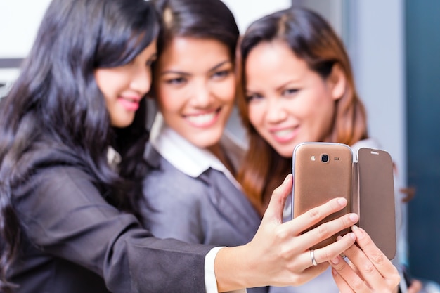 Asiatische Geschäftsfrauen, die selfie mit Smartphone nehmen