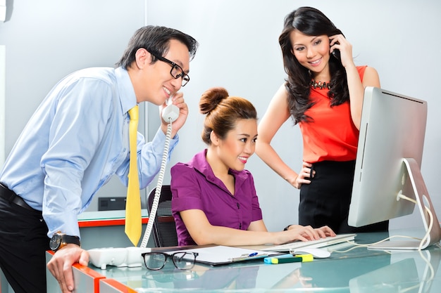 Asiatische Geschäftsleute in einem Büro arbeiten als Team zusammen, um in einem gemeinsamen Projekt erfolgreich zu sein