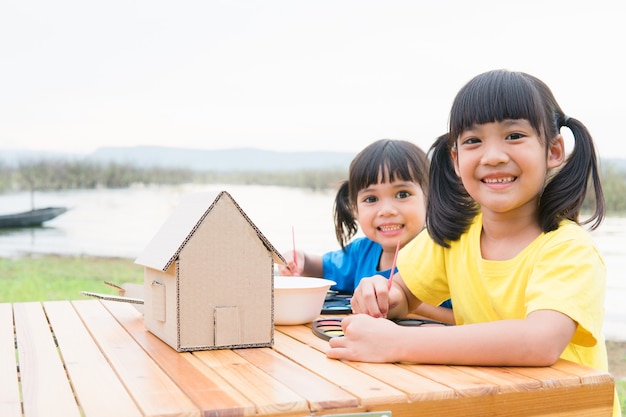 Asiatische geschwisterkinder zeichnen und malen farbe auf dem papier