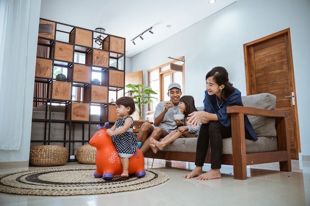 Asiatische glückliche Familie, die auf Sofa zu Hause sitzt und zusammen fernsieht