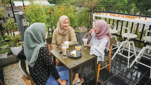 Asiatische gruppe hijab frau, die im café mit freund lächelt