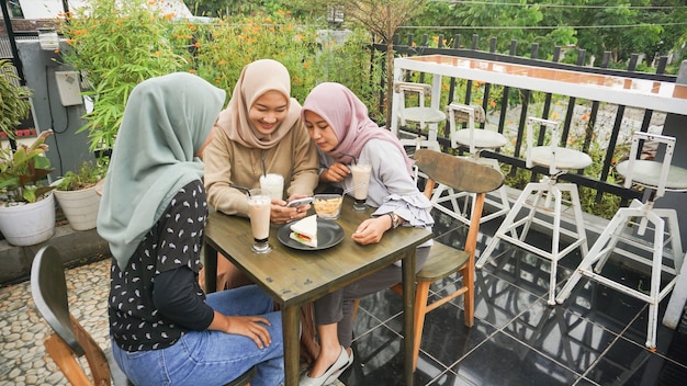 Asiatische Gruppe Hijab Frau, die im Café mit Freund lächelt