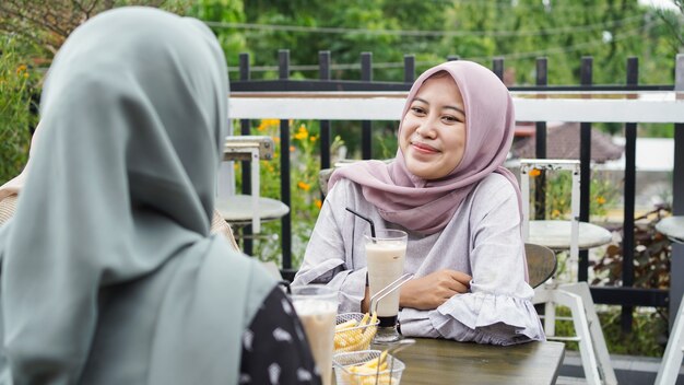 Asiatische Gruppe Hijab Frau, die im Café mit Freund lächelt