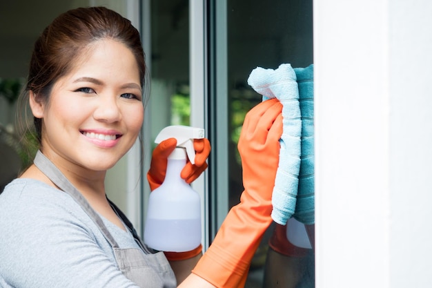 Asiatische Hausfrau putzt Fensterglas