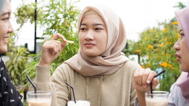 Asiatische Hijab-Frauengruppe, die im Café mit Freund lächelt