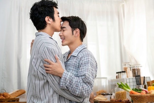 Asiatische homosexuelle Paare umarmen und küssen an der Küche morgens