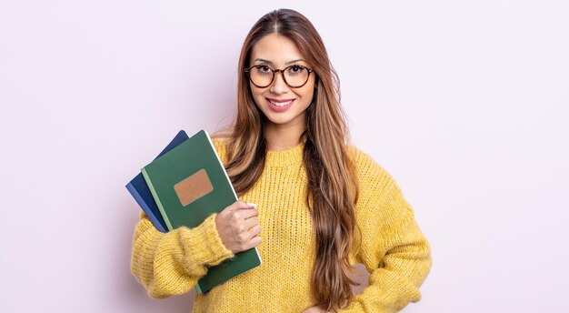 Asiatische hübsche Frau, die glücklich mit einer Hand auf Hüfte und überzeugt lächelt. studentisches Konzept