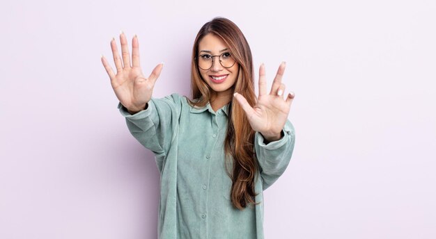 Asiatische hübsche Frau, die lächelt und freundlich aussieht, die Nummer acht oder acht mit der Hand nach vorne zeigt und herunterzählt