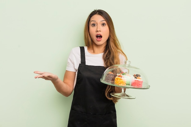 Asiatische hübsche Frau, die sich extrem schockiert und überrascht fühlt. Konzept für hausgemachte Kuchen