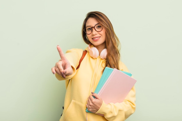 Asiatische hübsche Frau, die stolz und selbstbewusst lächelt und das Studentenkonzept Nummer eins macht